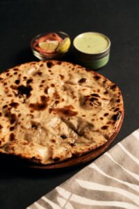 Close-up of Indian flatbread served with dips on a black background.