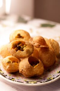 Close-up of traditional Indian snack panipuri with assorted fillings on a decorative plate.