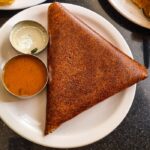 Delicious crispy dosa served with flavorful chutneys on a restaurant table in Dubai.