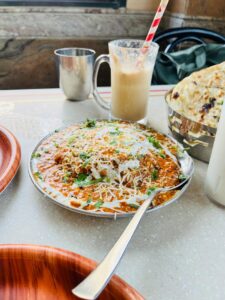 Mouthwatering Indian curry with cheese, naan, and a refreshing drink.